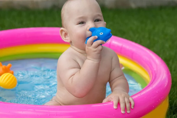 A small child is bathing in a pool, inflatable children\'s inflatable pool in summer