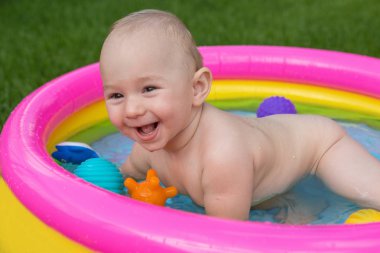 Küçük bir çocuk havuzda banyo yapıyor, yazın şişme çocukların şişme havuzunda.
