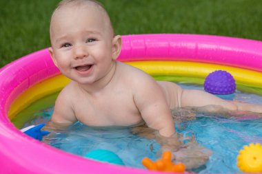 Küçük bir çocuk havuzda banyo yapıyor, yazın şişme çocukların şişme havuzunda.