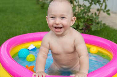 Küçük bir çocuk havuzda banyo yapıyor, yazın şişme çocukların şişme havuzunda.