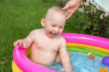 Küçük bir çocuk havuzda banyo yapıyor, yazın şişme çocukların şişme havuzunda.