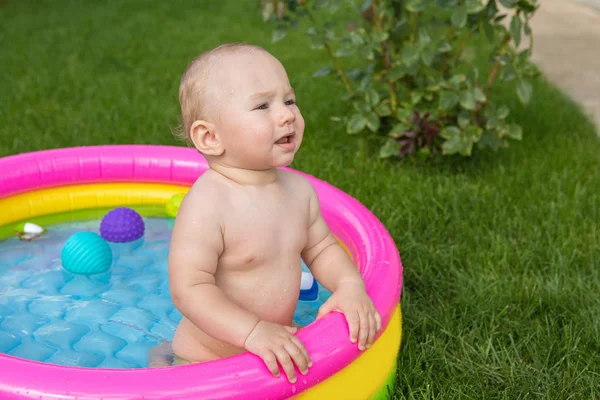 A small child is bathing in a pool, inflatable children\'s inflatable pool in summer