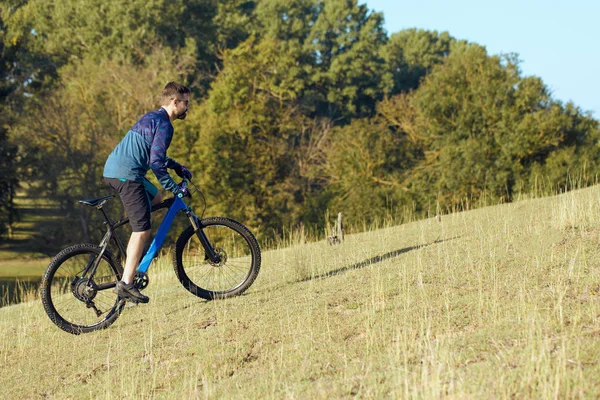 Cyclist in shorts and jersey on a modern carbon hardtail bike with an air suspension fork