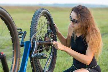 Kız bir dağ bisikleti offroad, güzel günbatımı, adlı bir bisikletçi portresi üzerinde açık Fitness kız bir modern karbon fiber dağ bisikleti sürmek..