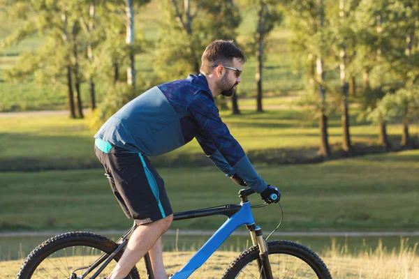 Cyclist in shorts and jersey on a modern carbon hardtail bike with an air suspension fork