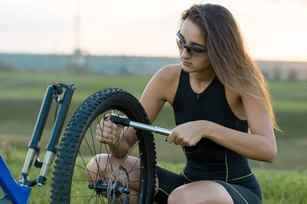 Kız bir dağ bisikleti offroad, güzel günbatımı, adlı bir bisikletçi portresi üzerinde açık Fitness kız bir modern karbon fiber dağ bisikleti sürmek..