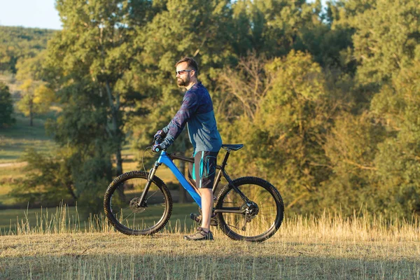 Cyclist in shorts and jersey on a modern carbon hardtail bike with an air suspension fork