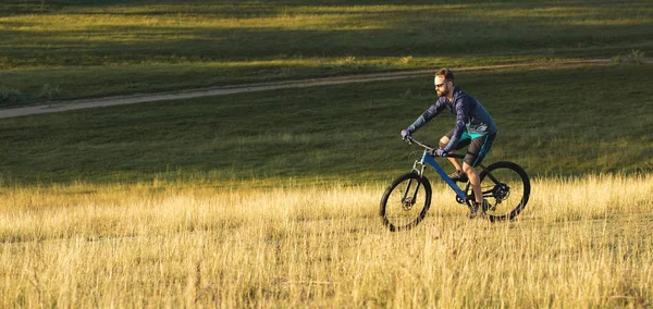 Cyclist in shorts and jersey on a modern carbon hardtail bike with an air suspension fork