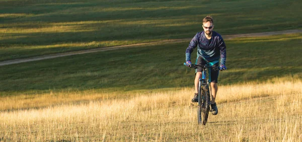 Cyclist in shorts and jersey on a modern carbon hardtail bike with an air suspension fork