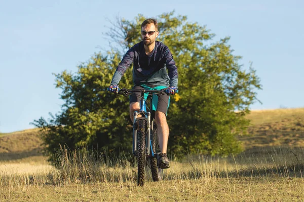 Cyclist in shorts and jersey on a modern carbon hardtail bike with an air suspension fork