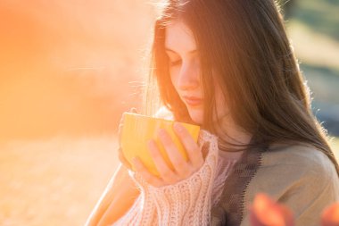 Güneşli Altın Sonbahar Orman üzerinde şık örme kazak duran genç ve güzel kadın portresi
