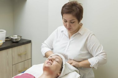 Yüz bakımı. Güzellik uzmanı güzellik salonunda fırça kullanarak yüzüne güzellik maskesi takıyor.