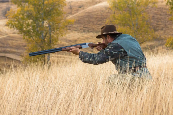 迷彩の銃と犬と草原で反射ベスト帽子のハンター — ストック写真