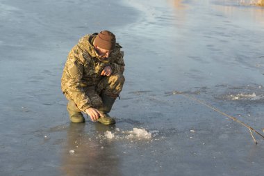 Kışın çukurda balık tutan adam küçük bir olta yakalar. Güzel bir kış gününde sazlıklarla gölde balık tutmak.