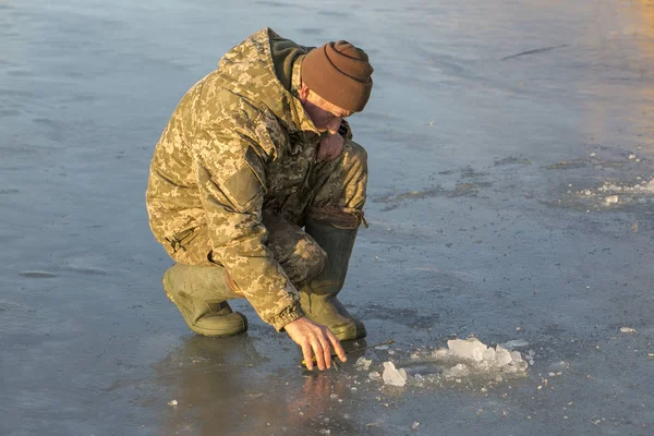 Kışın çukurda balık tutan adam küçük bir olta yakalar. Güzel bir kış gününde sazlıklarla gölde balık tutmak.