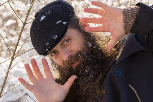 A man with a beard in the snow. Shows a thumbs up, delight.