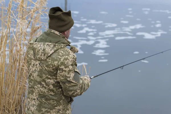 Рыбалка Тростнике Вращения Тихой Воде Человек Камуфляжной Одежде Прохладную Погоду — стоковое фото