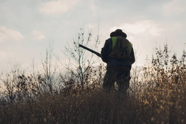 Şapkalı bir avcı kamuflaj silah ve bozkır bir yansıtıcı yelek