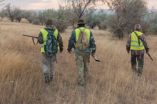 銃と丘の上の犬と つのハンター 反射チョッキ ハンター狩猟戦略を議論します — ストック写真