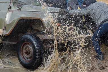 İnsanlar dışarıda SUV arabalarını çekiyorlar.