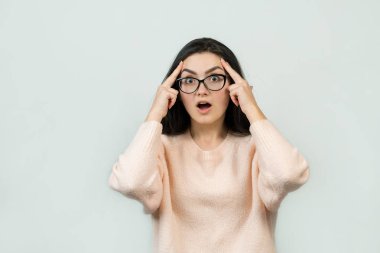 Mutlu genç beyaz kadın olarak pembe bir jumper. Bir kızla el eylem gri bir arka plan üzerinde duygusal portresi. Kavramsal iş saplama.