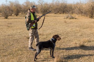 Şapkalı bir avcı kamuflaj silah ve bozkır bir yansıtıcı yelek