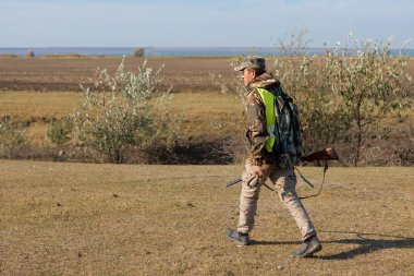 Şapkalı bir avcı kamuflaj silah ve bozkır bir yansıtıcı yelek