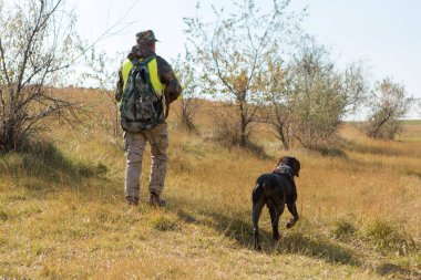 Şapkalı bir avcı kamuflaj silah ve bozkır bir yansıtıcı yelek