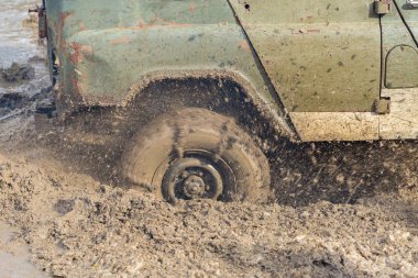 Bir SUV kir ve su tekerleklerin altında dışarı rips. Yakın çekim tüm arazi aracı.