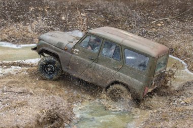 Bir SUV kir ve su tekerleklerin altında dışarı rips. Yakın çekim tüm arazi aracı.