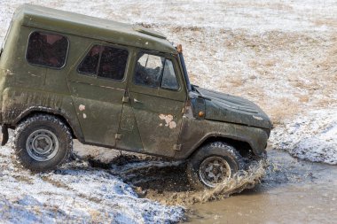 Bir SUV kir ve su tekerleklerin altında dışarı rips. Yakın çekim tüm arazi aracı.