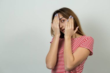 Çizgili tişört içinde güzel bir kızın portresi. Bir kızla el eylem gri bir arka plan üzerinde duygusal portresi. Kavramsal iş saplama.