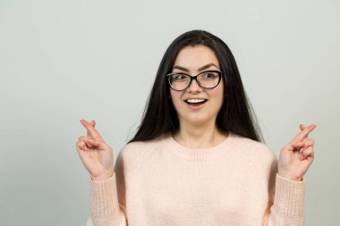 Mutlu genç beyaz kadın olarak pembe bir jumper. Bir kızla el eylem gri bir arka plan üzerinde duygusal portresi. Kavramsal iş saplama.