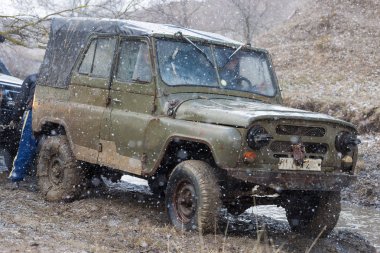 Rally on Russian SUVs in the mud in winter, Trapped all-terrain vehicle pulled out of the river    clipart