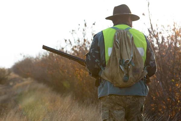 帽子と 草原で獲物を捜して銃ハンターが獲物を目指しています — ストック写真