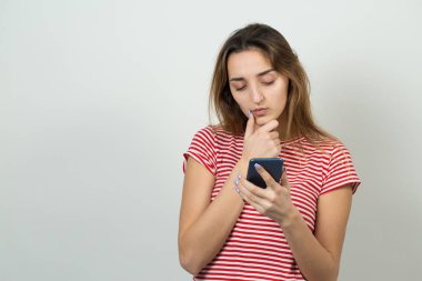 Beyaz arka planda akıllı telefondan izleyen beyaz bir kız.