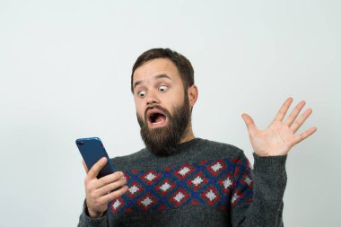 Beyaz arka planda akıllı telefon kullanan korkmuş beyaz sakallı genç adam.