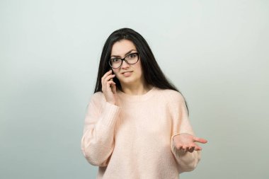 Gözlüklü beyaz kız beyaz arka planda akıllı telefondan konuşuyor.