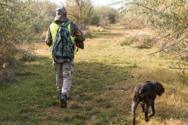 Tüfekli erkek avcı ve açık havada köpek avı.