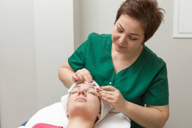 Yüz bakımı. Güzellik uzmanı güzellik salonunda fırça kullanarak yüzüne güzellik maskesi takıyor.