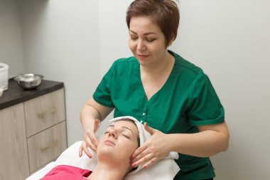 Yüz bakımı. Güzellik uzmanı güzellik salonunda fırça kullanarak yüzüne güzellik maskesi takıyor.