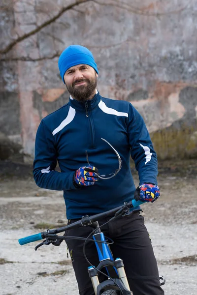 ヴィンテージレンガのコンクリートの壁に空気懸濁フォークで現代の山のカーボンバイクで服に乗ったスポーツウェアの男 — ストック写真