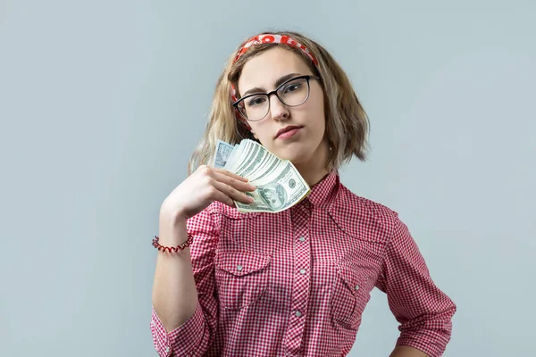 年轻美女在眼镜与美元钱在灰色背景手中的红色格子衬衫特写 — 图库照片