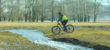 Parkta bisiklete binen genç adam 