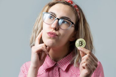 beautiful young blonde caucasian girl wear glasses holding crypto coin on white background