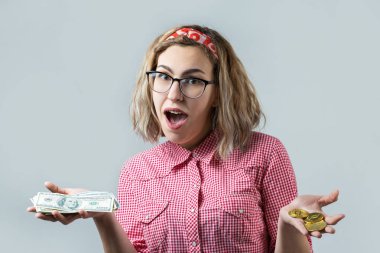 beautiful young blonde caucasian girl wear glasses holding crypto coins and dollar banknotes on white background