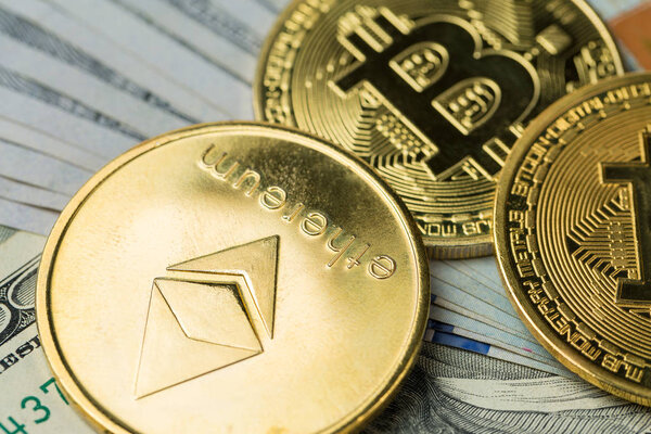 золотые монеты криптовалюты - Bitcoin, Ethereum, Litecoin на фоне 100-долларовой купюры. Концепция виртуальных денег.