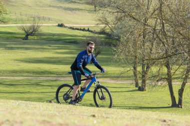 Taze yeşil yaz ormanının arka planına karşı bir uçurumun üzerinde duran bir hava süspansiyon çatal ile modern bir karbon hardtail bisiklet üzerinde şort ve mayo Bisikletçi