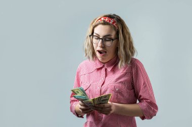 Young caucasian blonde woman in glasses with dollar banknotes on white background