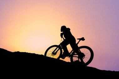Şort ve mayo modern bir karbon hardtail bisiklet üzerinde bir hava süspansiyon çatal sürmek off-road turuncu-kırmızı tepelerde yaz aylarında gün batımı akşamı